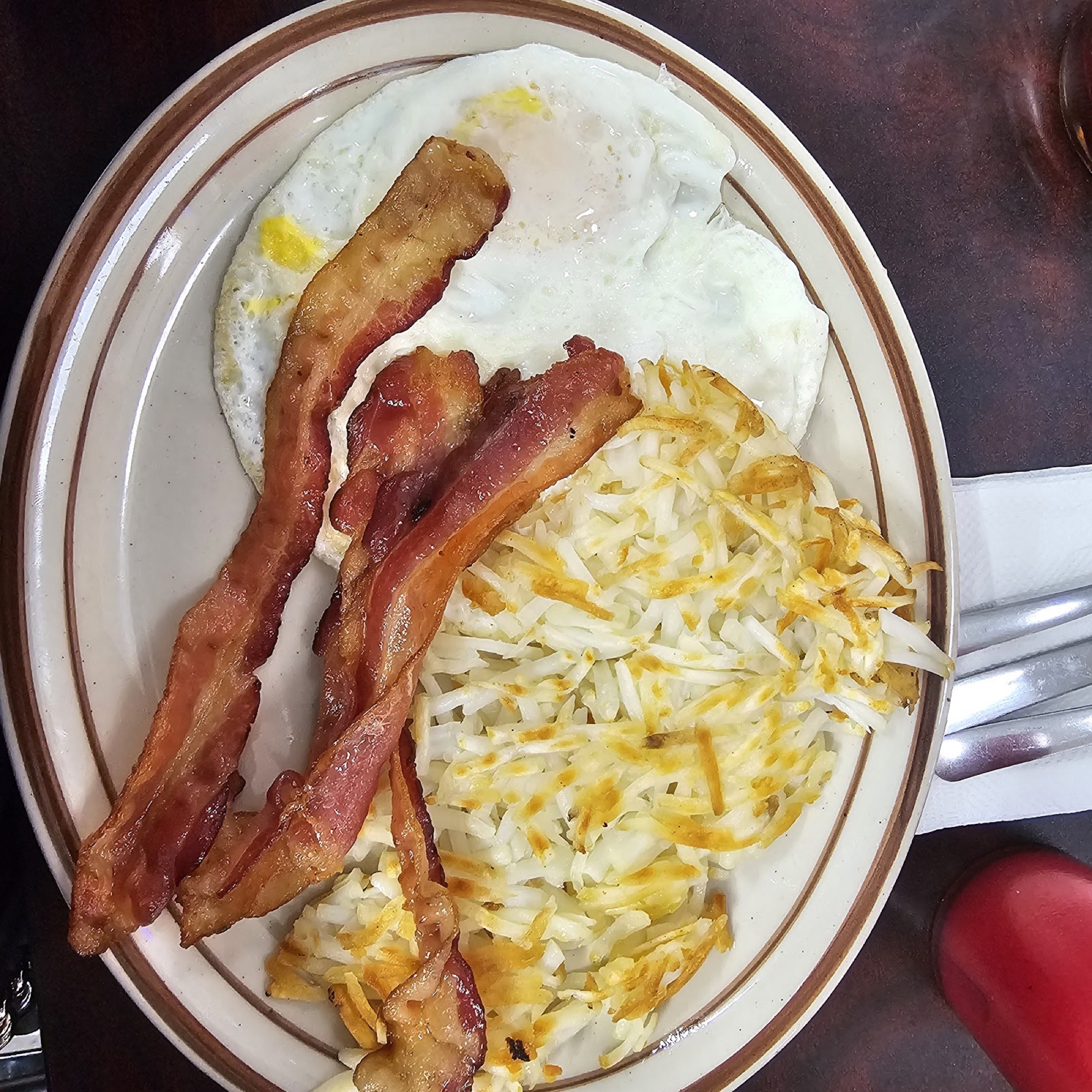 Two eggs over easy with bacon and golden hash browns.