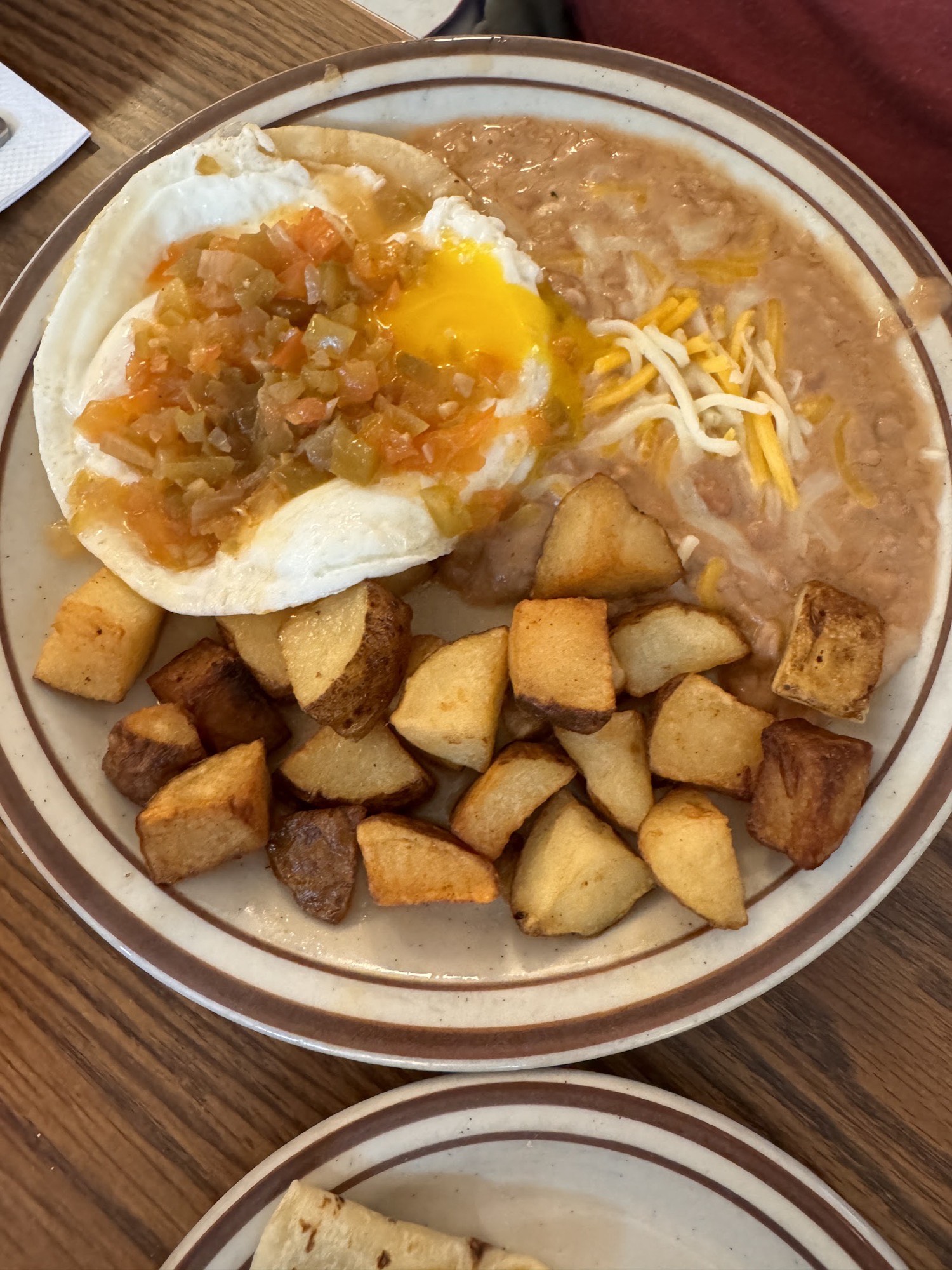 Huevos rancheros: eggs topped with salsa over a tortilla, with refried beans, cheese and breakfast potatoes.